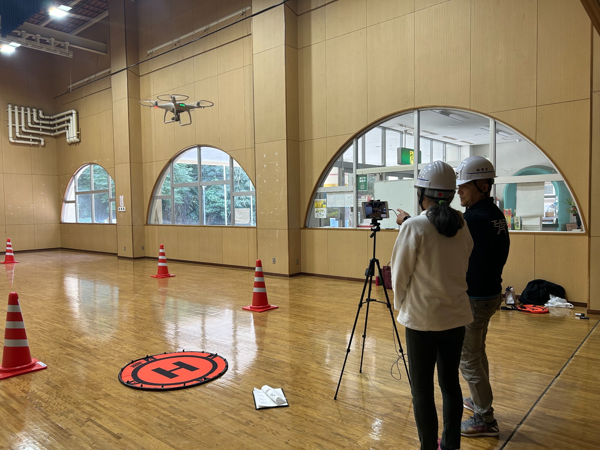 屋内で講師と一緒にドローンを操縦する体験の様子